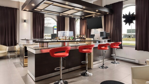 Una zona de bar moderna con una barra central, taburetes y un televisor de pantalla plana.
