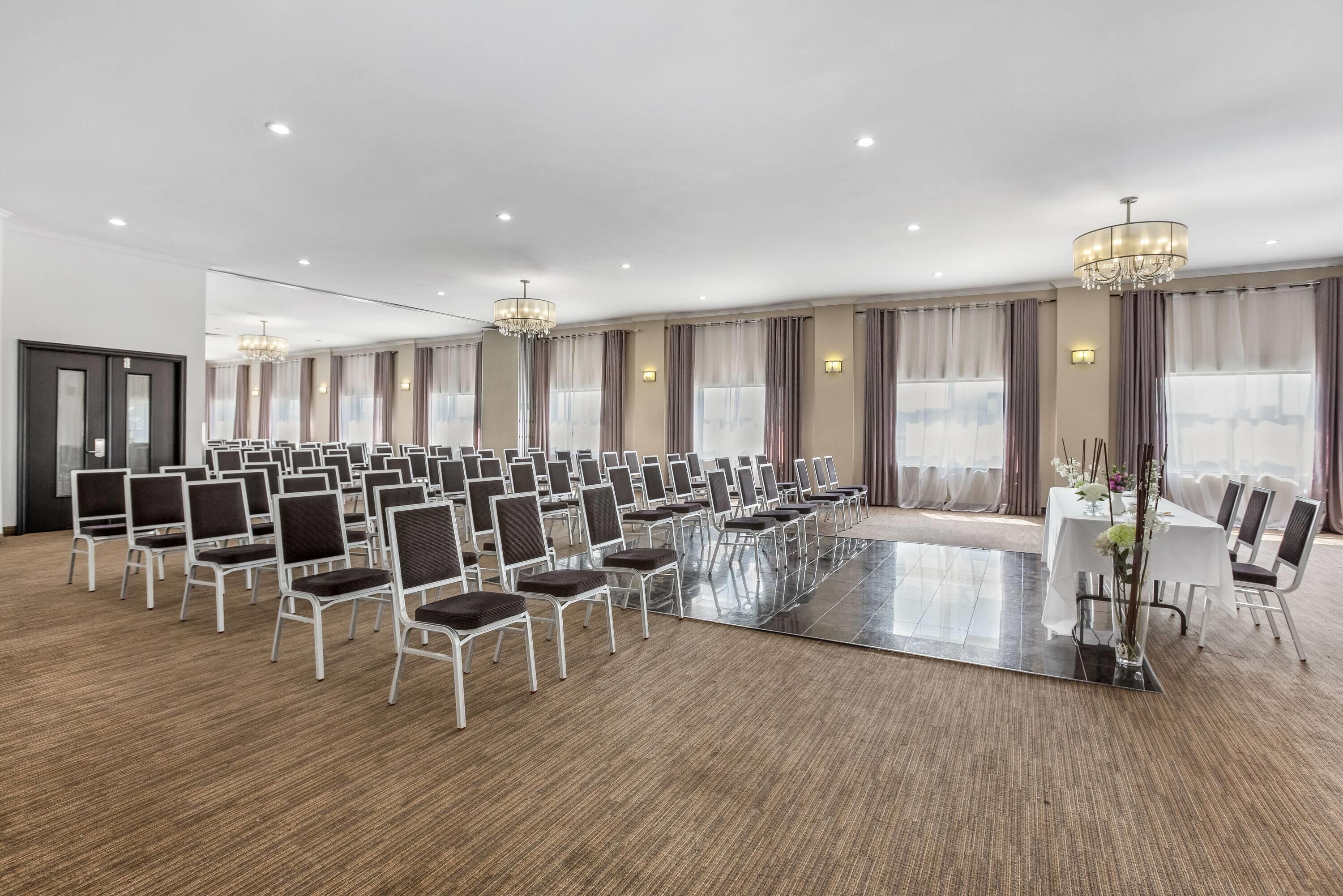 A large conference room with rows of chairs, a central table, and chandeliers.