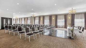 A large conference room with rows of chairs, a central table, and chandeliers.