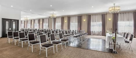 Un amplio salón de conferencias con filas de sillas, una mesa central y candelabros.