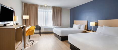 A hotel room with two beds, a desk, a chair, a television, and a window with curtains.