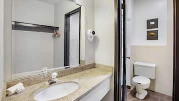 Baño con lavamanos, espejo, inodoro y una cámara de seguridad.