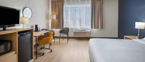 Une chambre d’hôtel équipée d’un lit, d’un bureau, d’une chaise, d’une télévision et d’une fenêtre avec des rideaux.