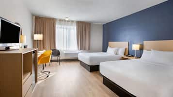 Una habitación de hotel con dos camas, un escritorio, una silla y un televisor.