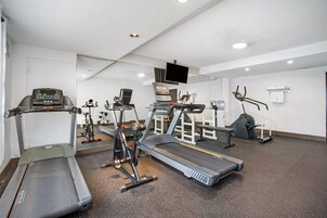 Un gimnasio con cintas de correr, bicicletas estáticas y máquinas de pesas.