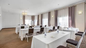 A conference room with multiple tables, chairs, and a chandelier.
