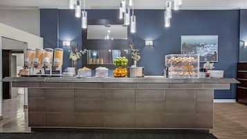 A reception area with a counter displaying food items, a mirror, and wall-mounted lights.
