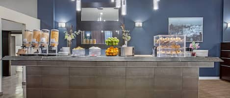 Un área de recepción con un mostrador que exhibe alimentos, un espejo e iluminación en la pared.
