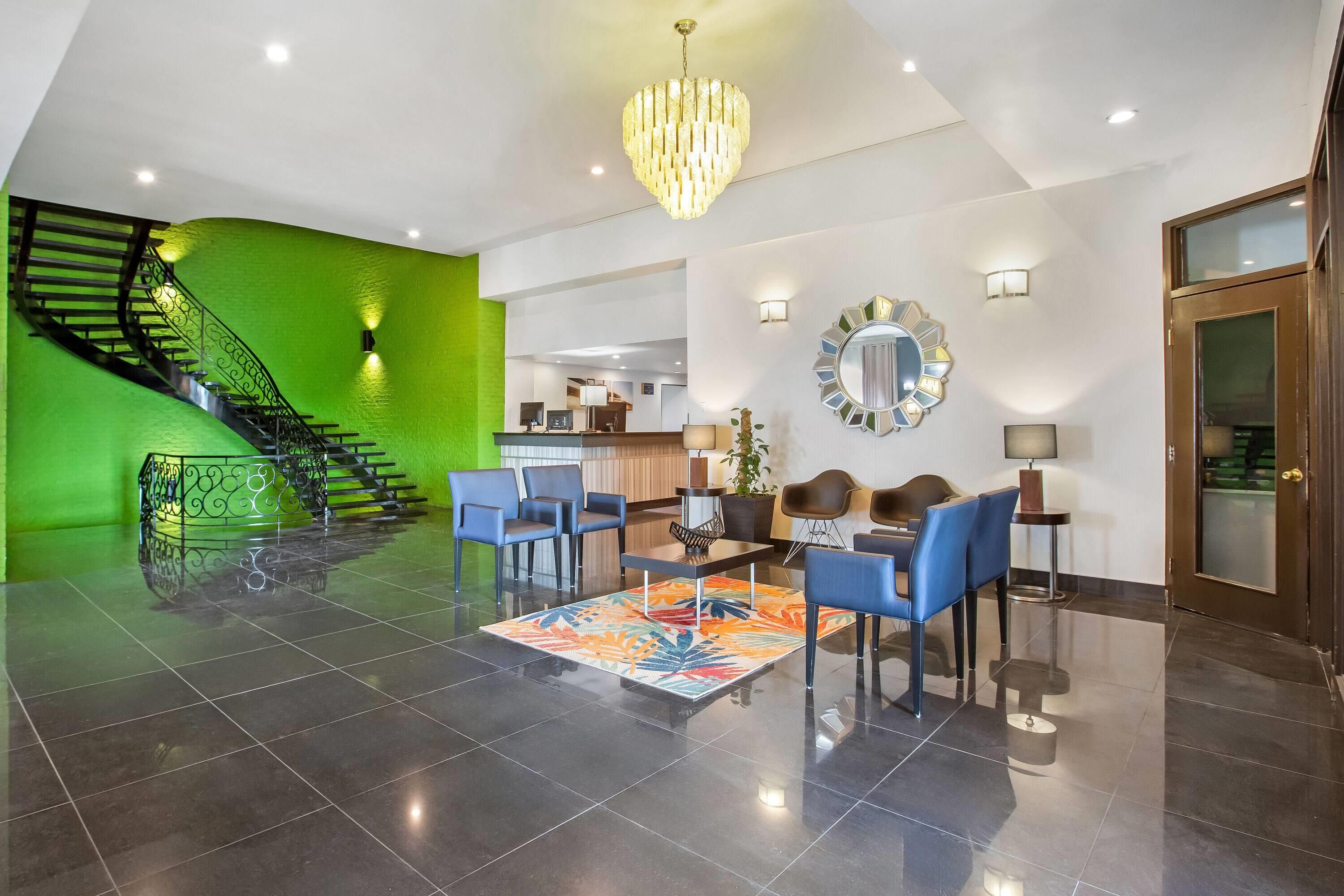 Un hall d’entrée spacieux avec un escalier, un coin salon et un comptoir d’accueil.