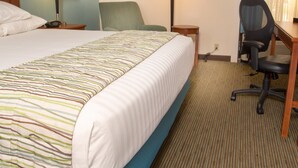 A hotel room with a large bed, two bedside tables, a desk with a chair, and two lamps. - Drury Inn & Suites Cape Girardeau (Cape Girardeau)