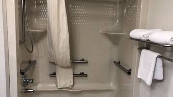 A bathtub with a shower head, a towel rack, and a shelf with towels.