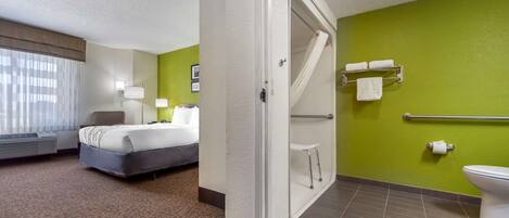 Habitación de hotel con cama, baño con inodoro y toallero, y ventana con cortinas.