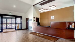 A reception area with a wooden reception desk, a sign for 'Sleep Inn', and a large glass door leading outside.