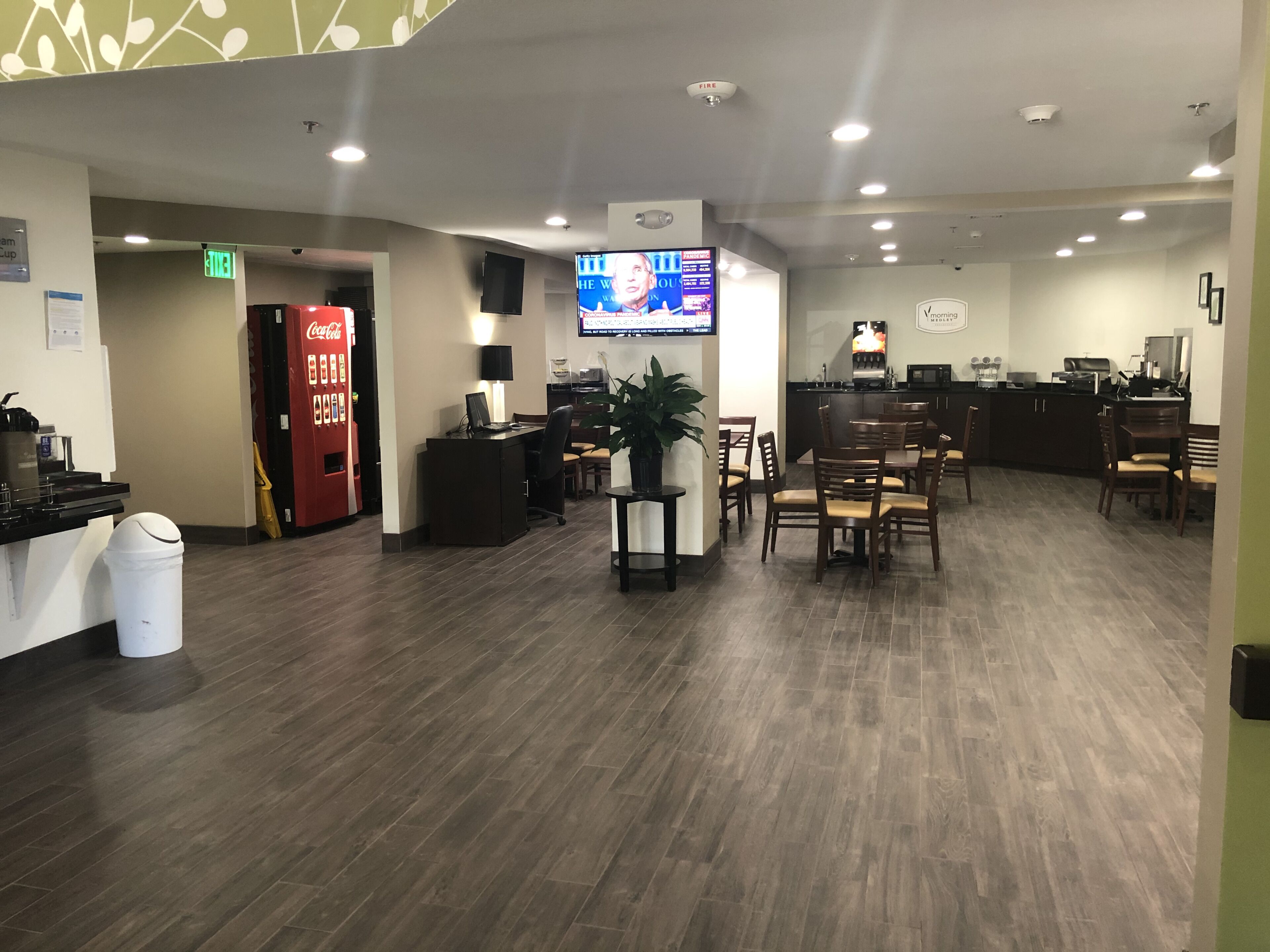 A hotel lobby with a reception desk, seating area, and a Coca-Cola vending machine.