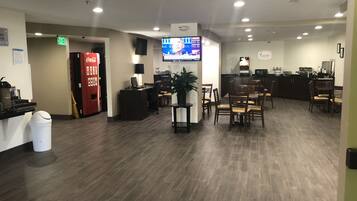 A hotel lobby with a reception desk, seating area, and a Coca-Cola vending machine.