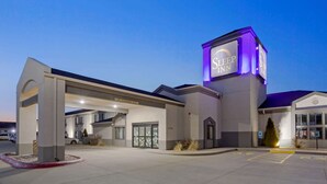A hotel entrance with a prominent sign, a covered parking area, and a clear view of the building's facade.