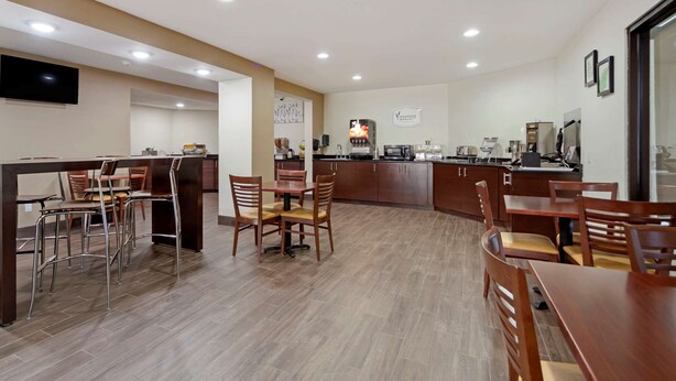 A modern hotel dining area with a central island, bar, and seating.
