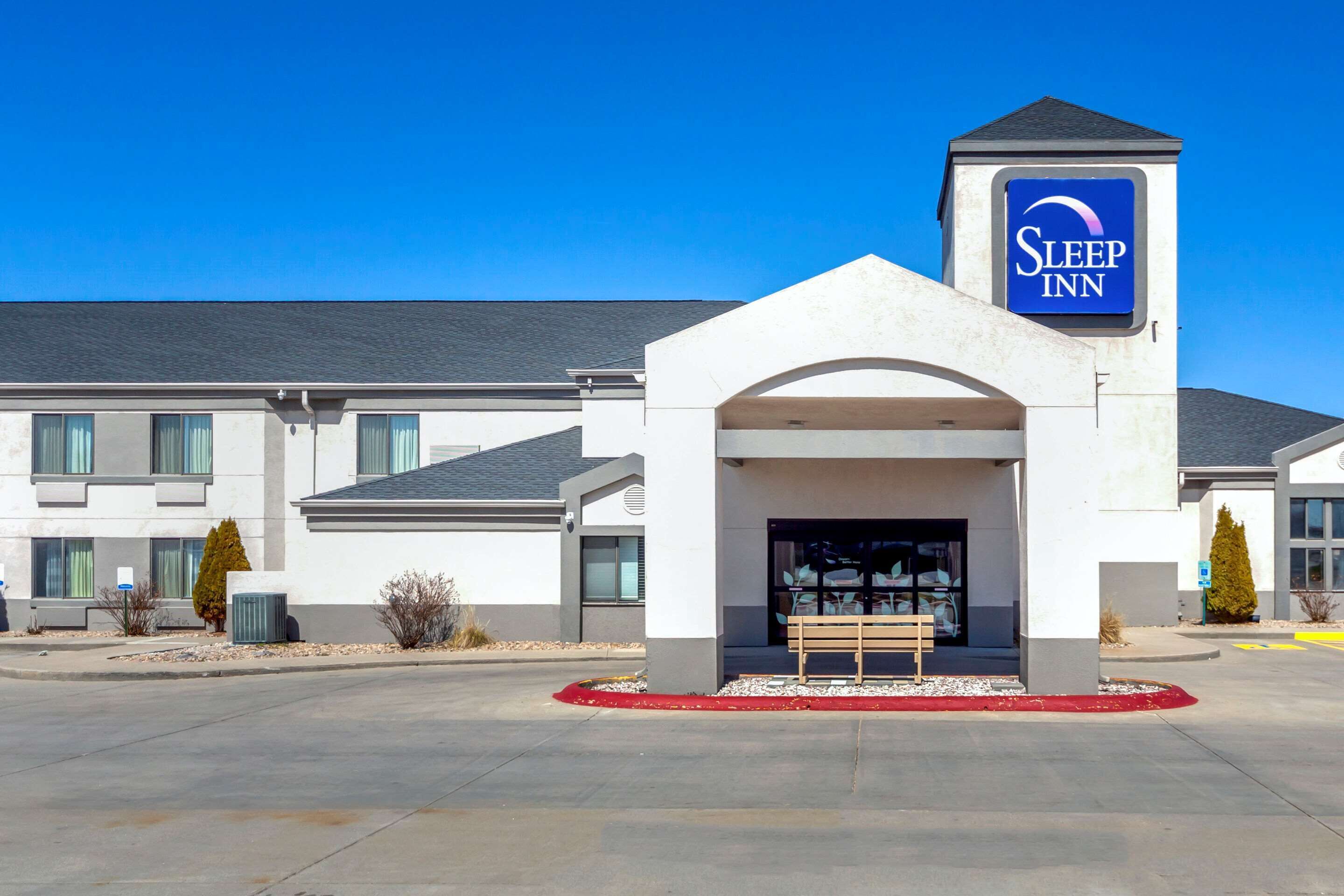 A Sleep Inn hotel with a modern design, featuring a prominent entrance and a clear blue sky.