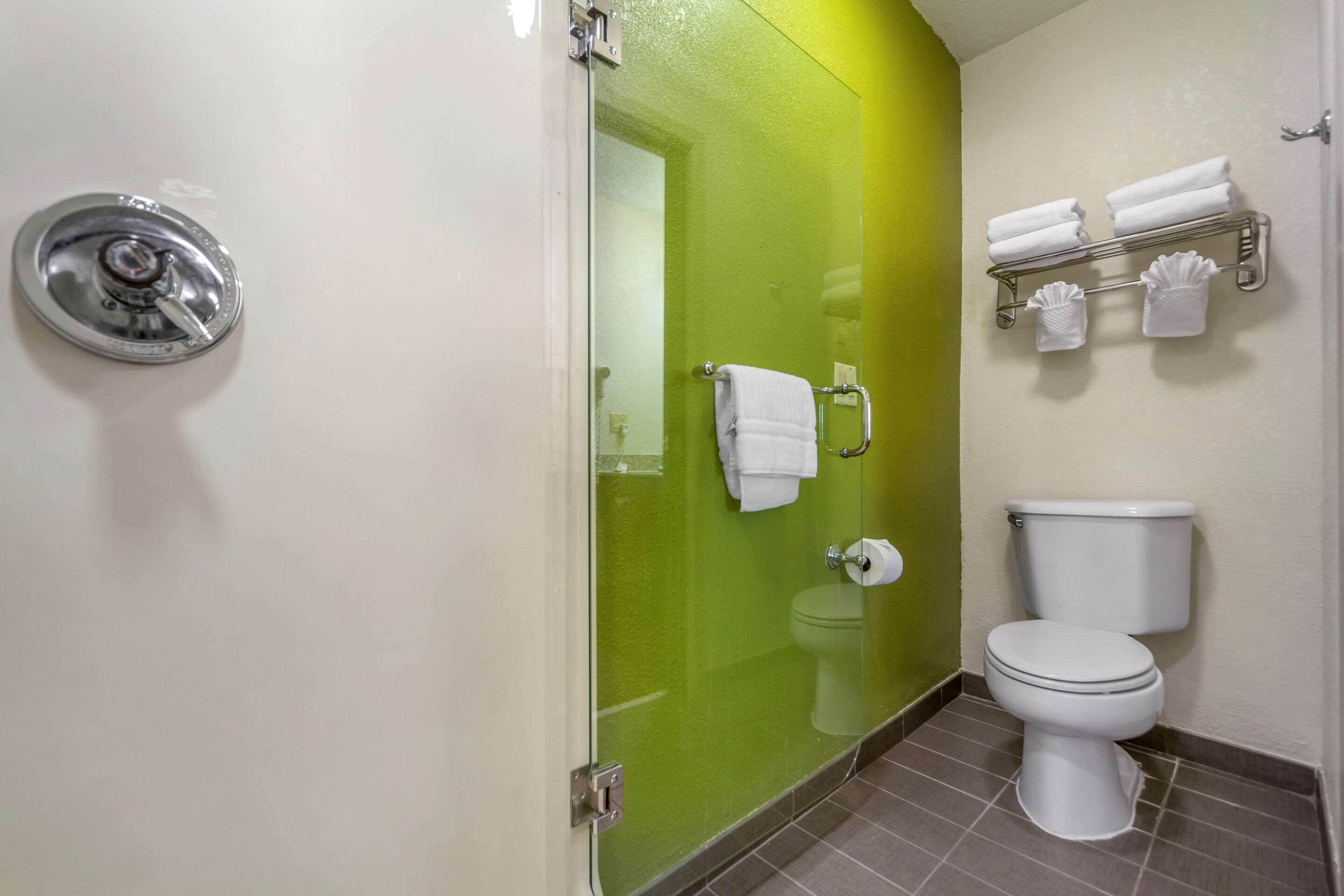 A bathroom with a glass shower door, a toilet, and a towel rack with towels.