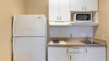 A compact kitchen with a white refrigerator, a microwave, a sink, and a countertop.