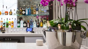 Un espace bar comprenant un assortiment de bouteilles d’alcool, un comptoir et une composition florale décorative à base d’orchidées.