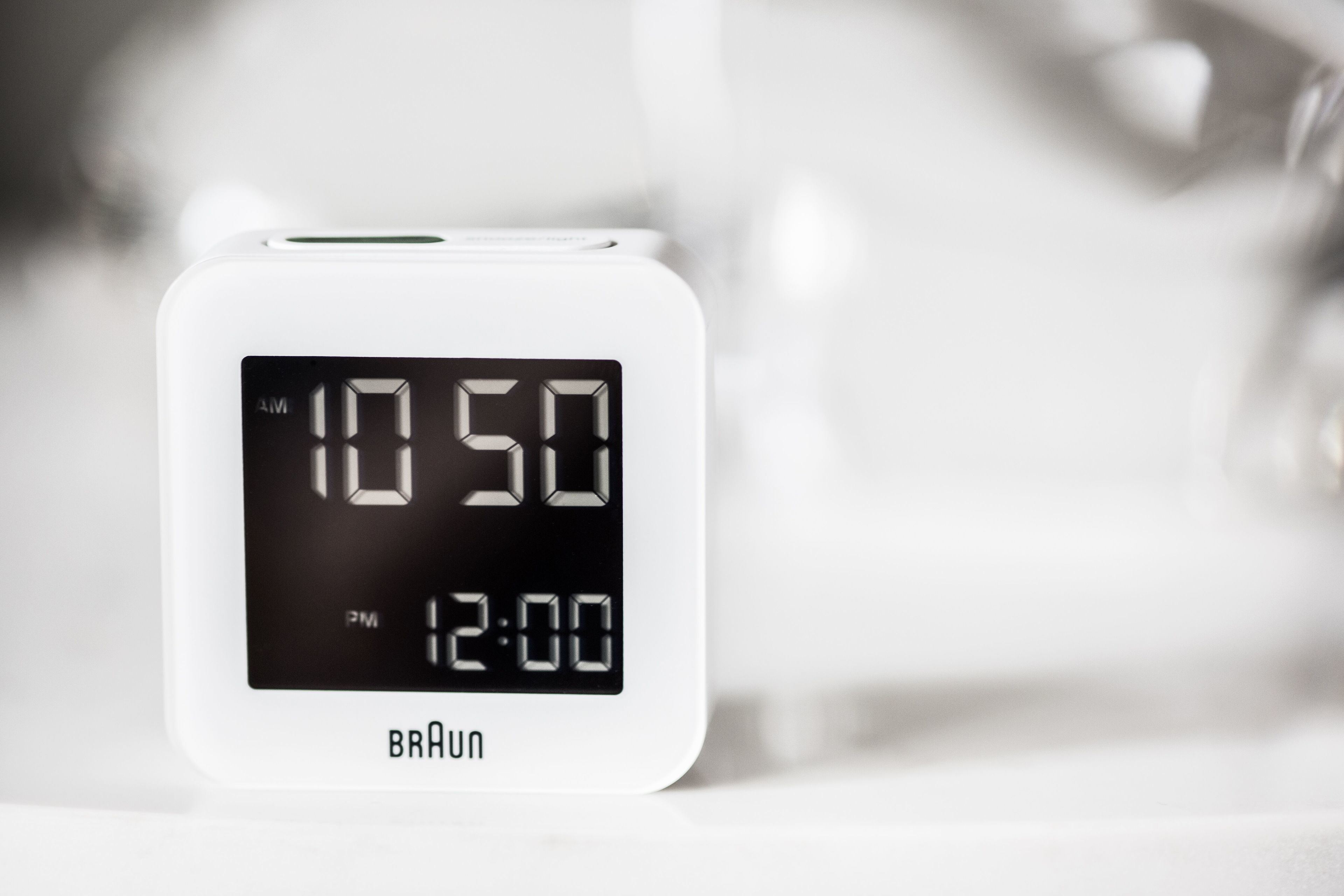 A white Braun digital clock displaying 10:50 AM and 12:00 PM.
