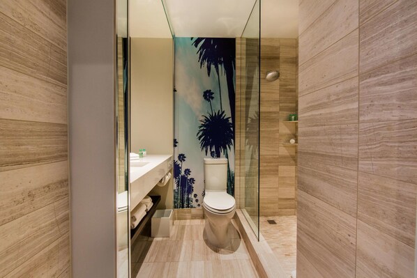 A modern bathroom with a glass shower enclosure, a toilet, and a vanity with a towel rack.