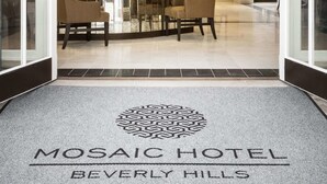 Zona de recepción de un hotel con diseño moderno, que incluye una lámpara de araña, un mostrador de recepción y un área de estar con sillas.