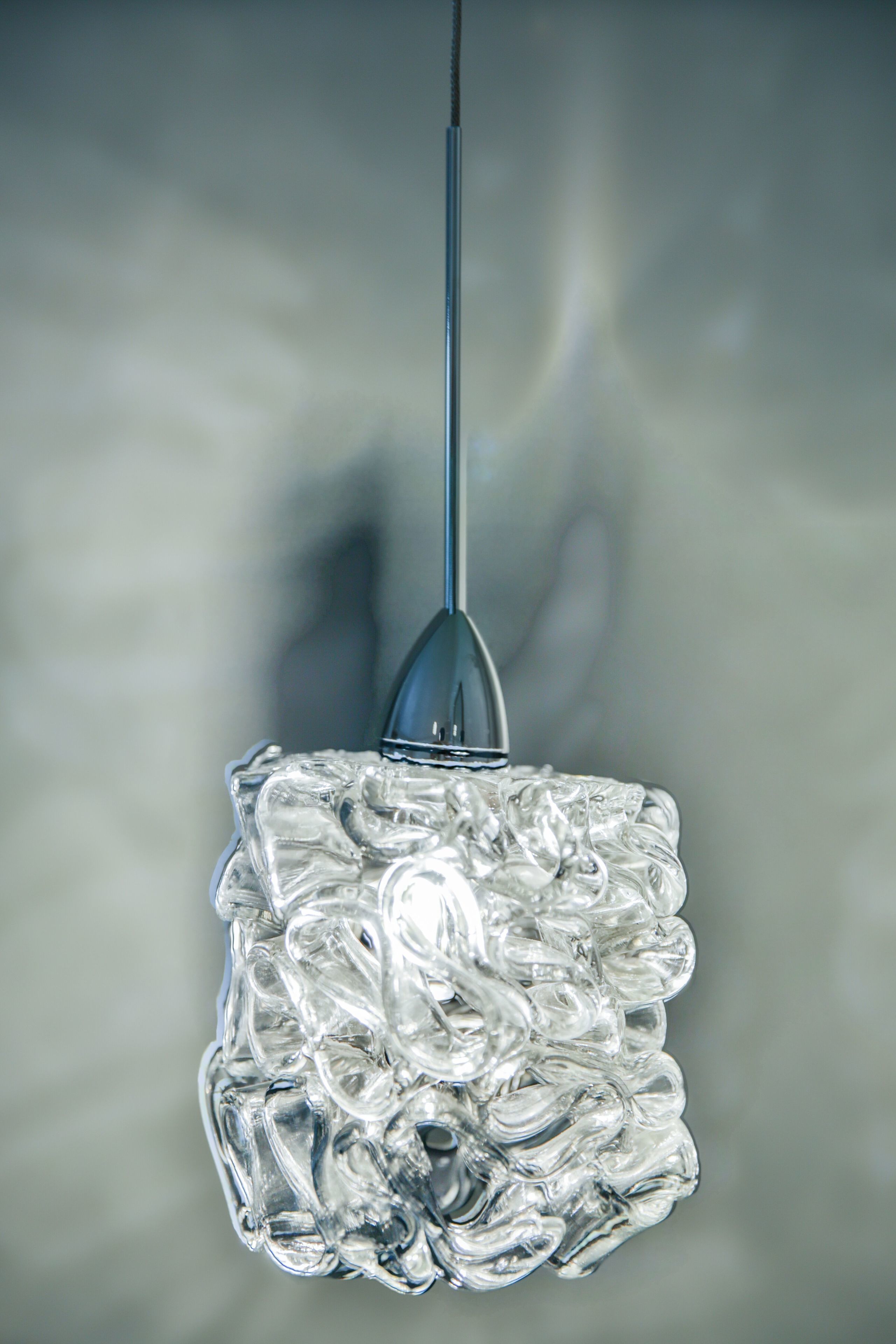 Un lustre en verre transparent, à motifs géométriques, suspendu au plafond.
