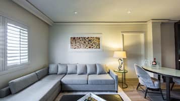 Una sala de estar moderna con un sofá gris, una mesa de centro de vidrio y una mesa de comedor con sillas.