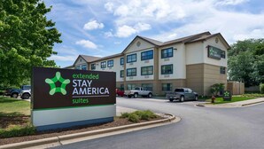 A sign for Extended Stay America suites with a building in the background.