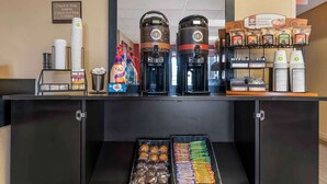 A breakfast bar with coffee makers, a sign indicating check-in and check-out times, and a variety of food and drink options.