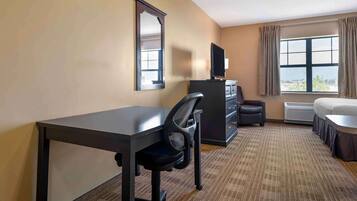 Una habitación de hotel con escritorio, silla, cómoda, televisor y cama.