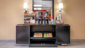A self-service beverage station with coffee makers, a mirror, and a display of snacks.