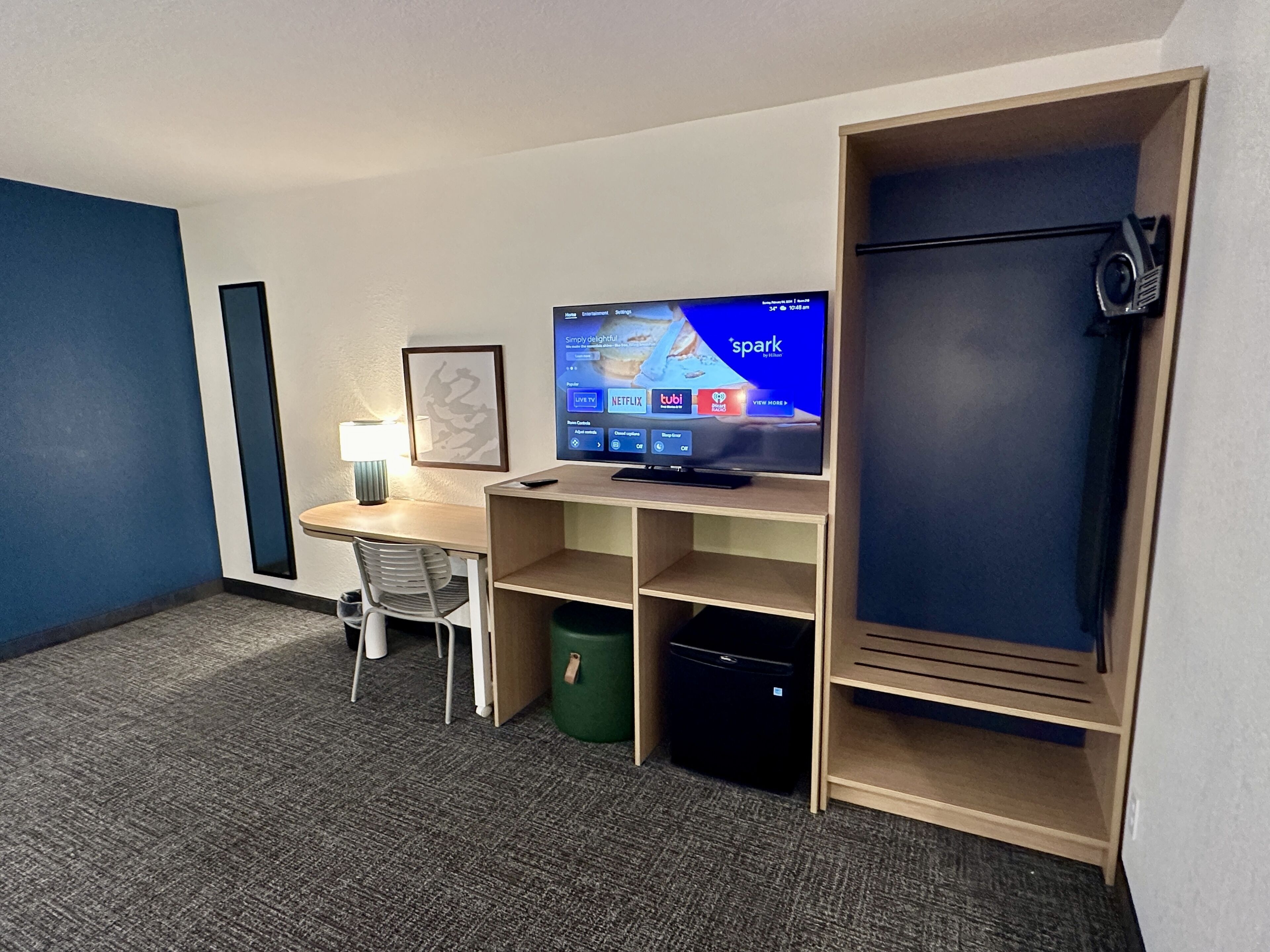 Une chambre d’hôtel équipée d’un bureau, d’un téléviseur permettant d’accéder à des services de diffusion en continu, d’une chaise et d’une armoire.