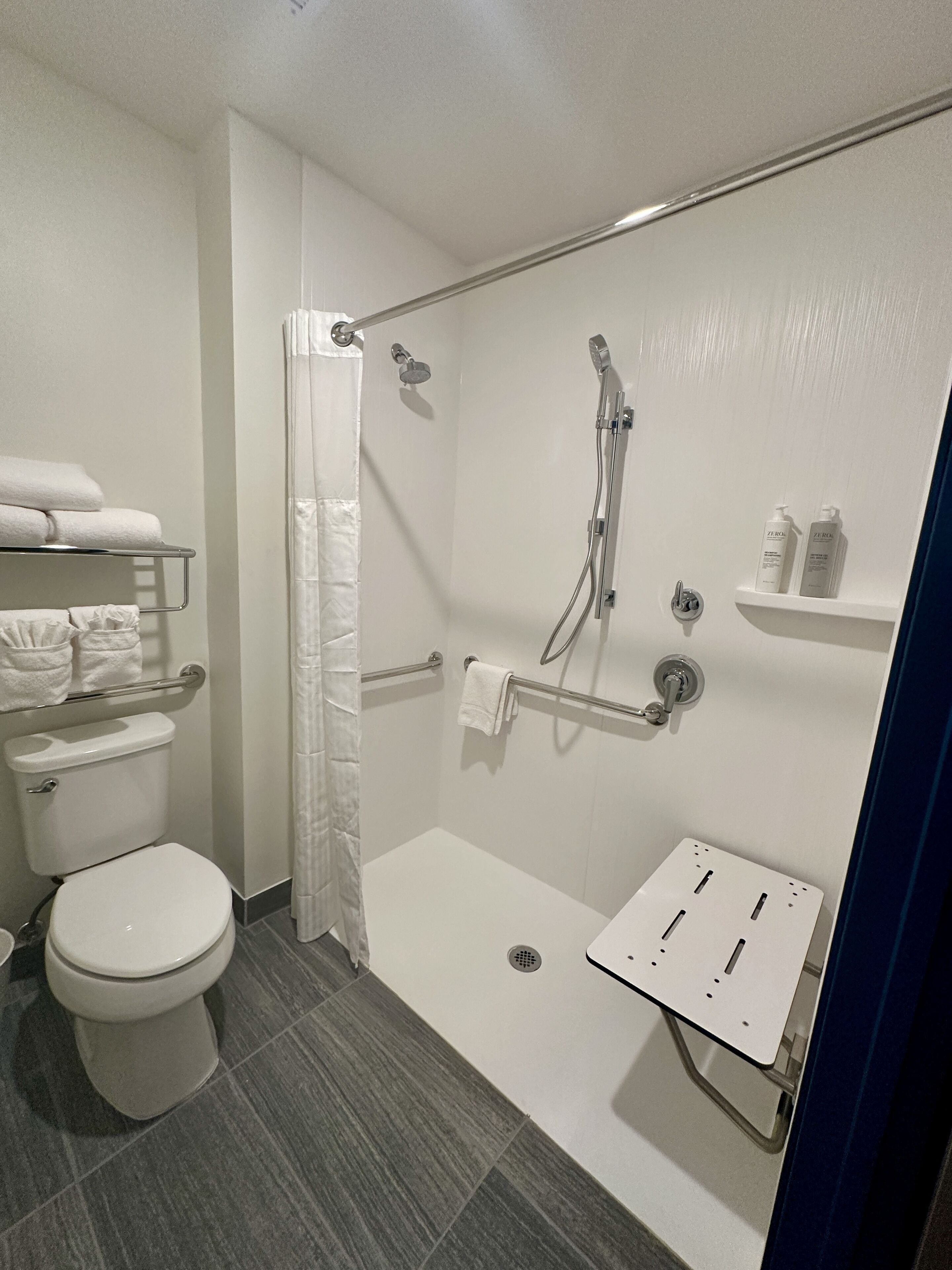 Un baño moderno con ducha, inodoro y perchero para toallas.
