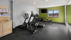 Een fitnessruimte met loopbanden, een hometrainer en een bankdrukrek.