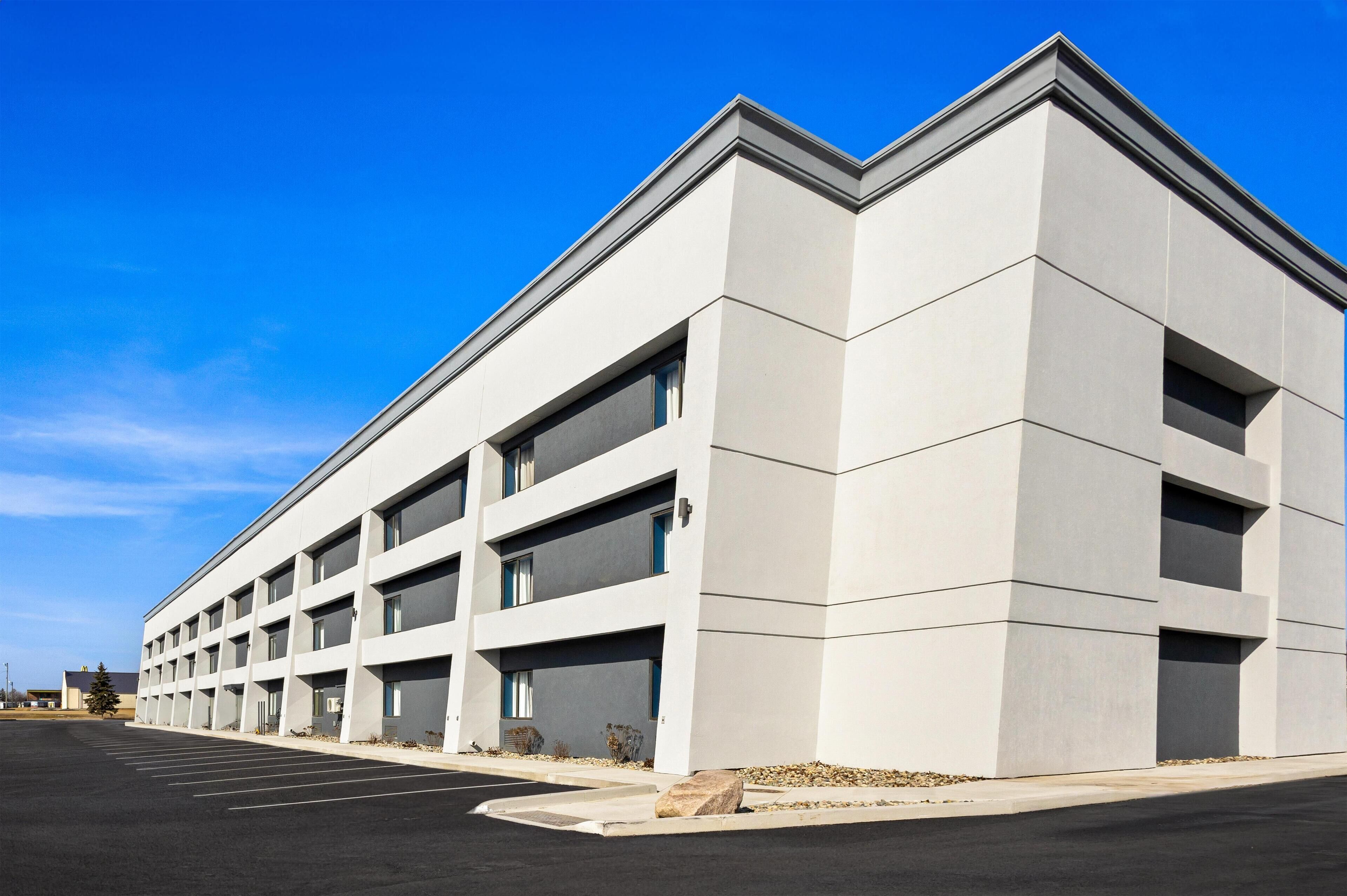 A modern building with a flat roof and a parking lot in front.