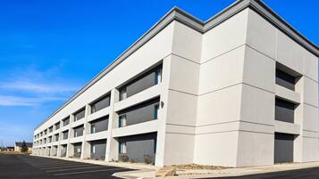 A modern building with a flat roof and a parking lot in front.