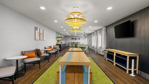 Een modern interieur met een lange houten tafel, verschillende zithoeken en een aan de muur bevestigde televisie.