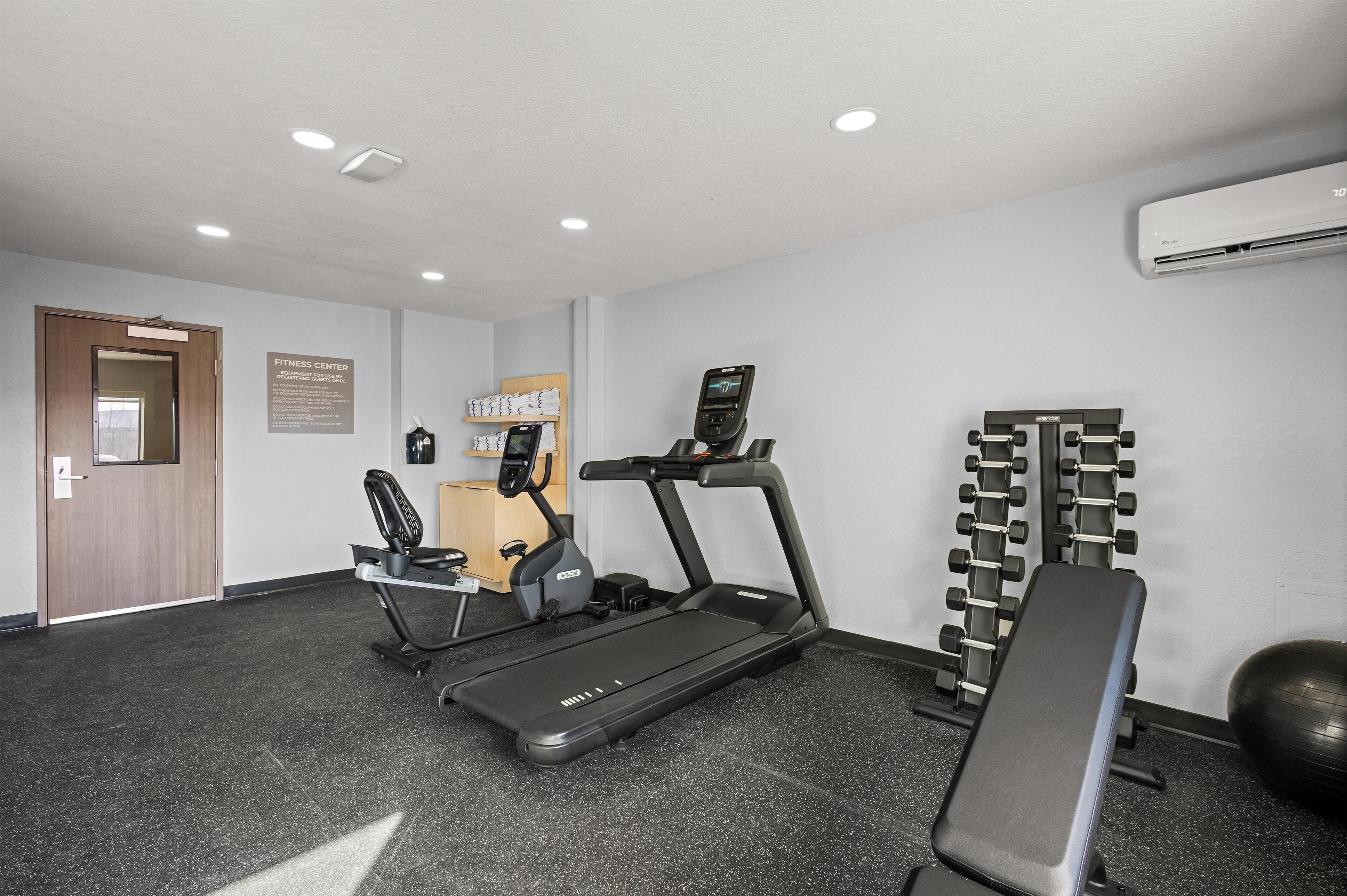 A fitness center with treadmills, a bench, and weightlifting equipment.