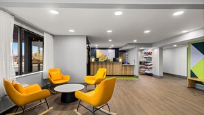 Een moderne kantoorruimte met een receptiegedeelte, houten vloeren en gele schommelstoelen rond een centrale tafel.