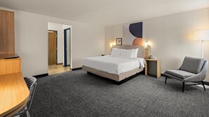 Een hotelkamer met een bed, een bureau, een stoel en een lamp.