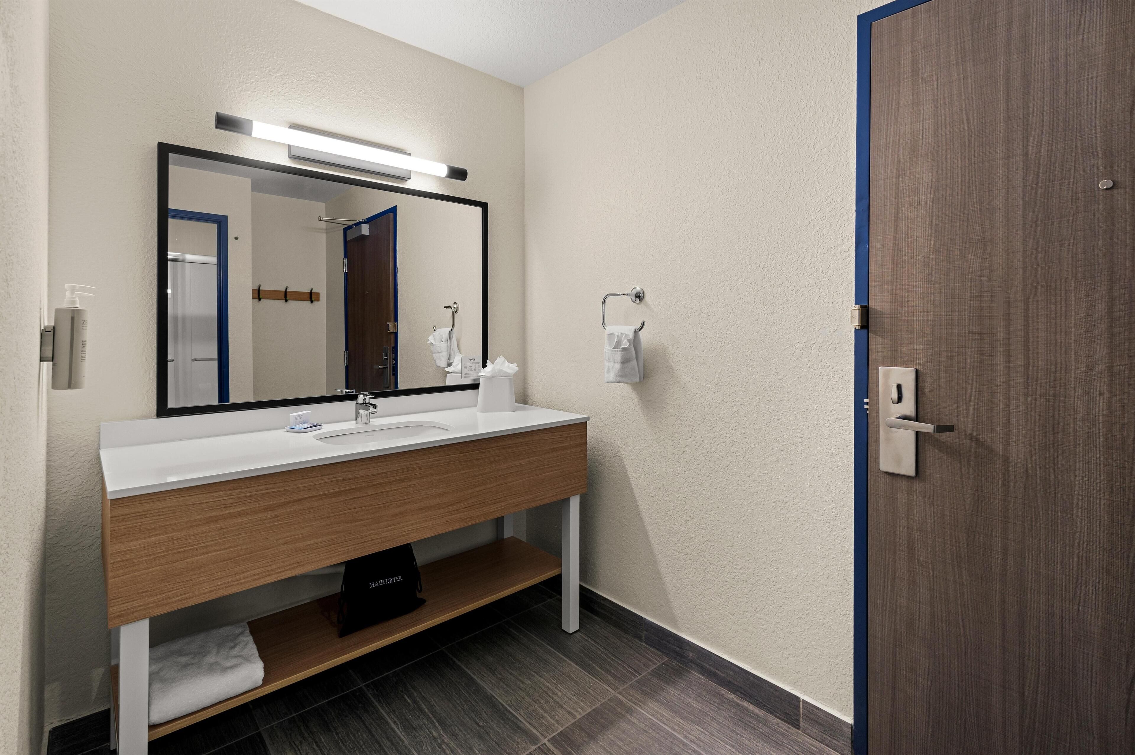 A modern bathroom with a white sink, mirror, and wooden vanity.
