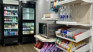 Una tienda con estantes llenos de aperitivos y agua embotellada, además de dos refrigeradores con bebidas.