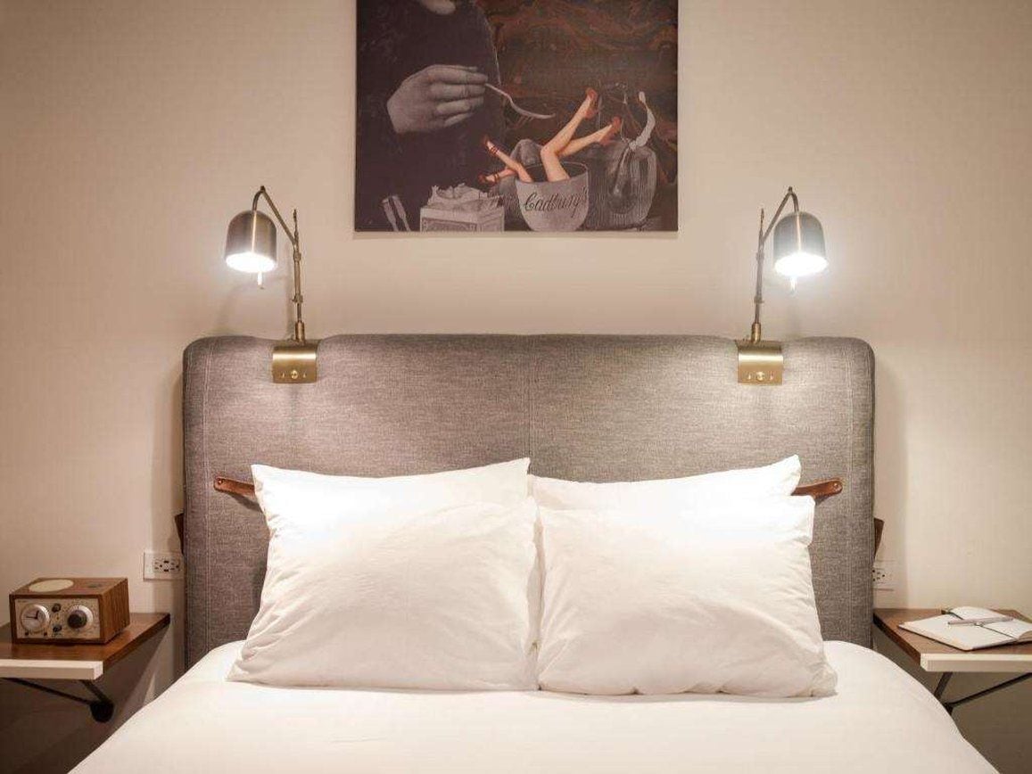 A bed with two white pillows, a grey headboard, and two bedside lamps.
