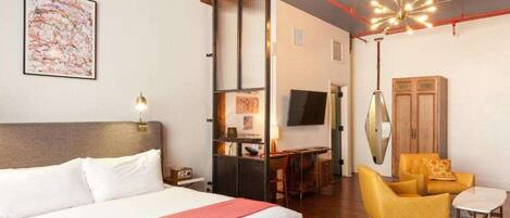 A hotel room with a bed, a desk, a chair, a television, and a ceiling fan.