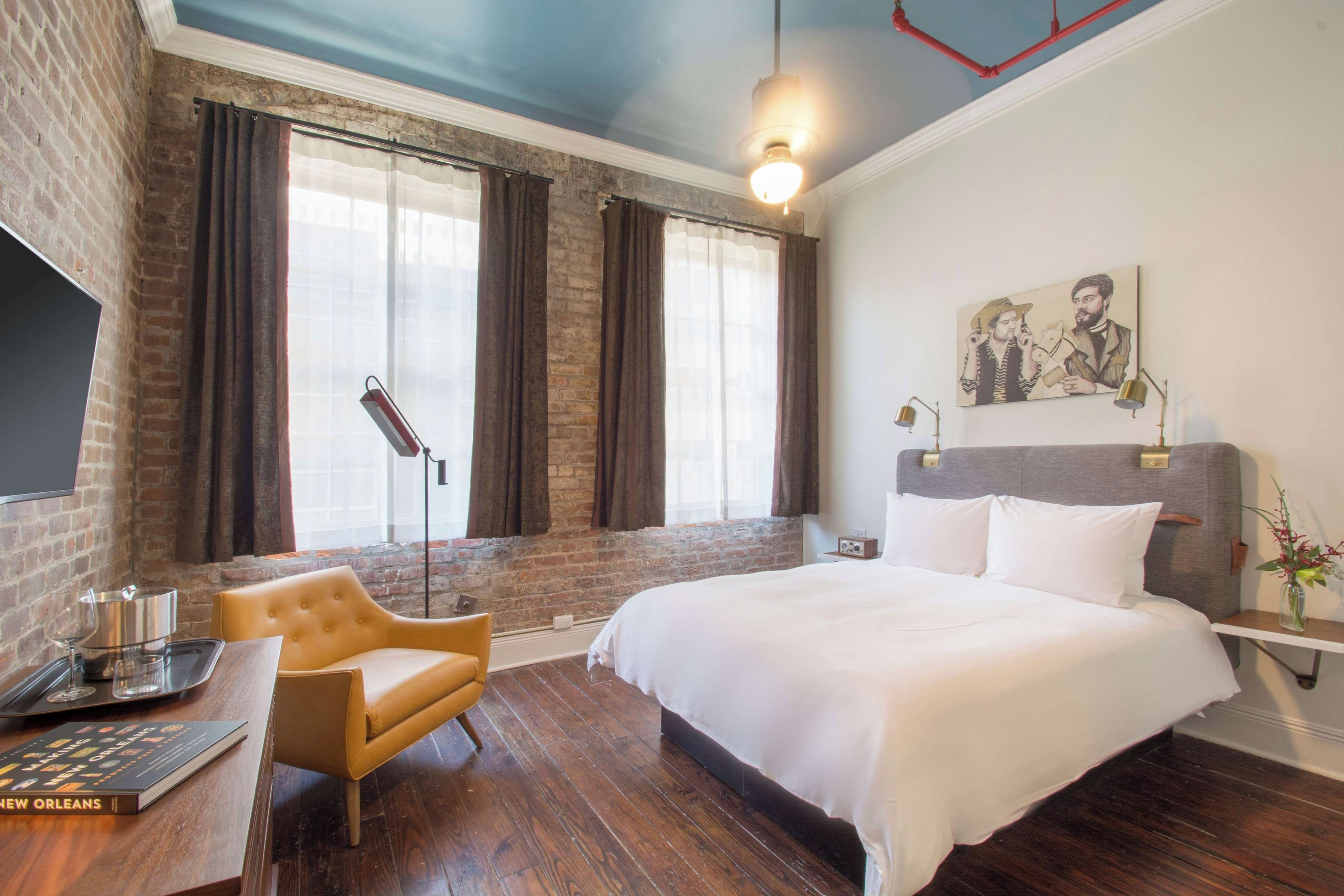 A hotel room with a large bed, a desk with a chair, a flat-screen TV, and a painting on the wall.