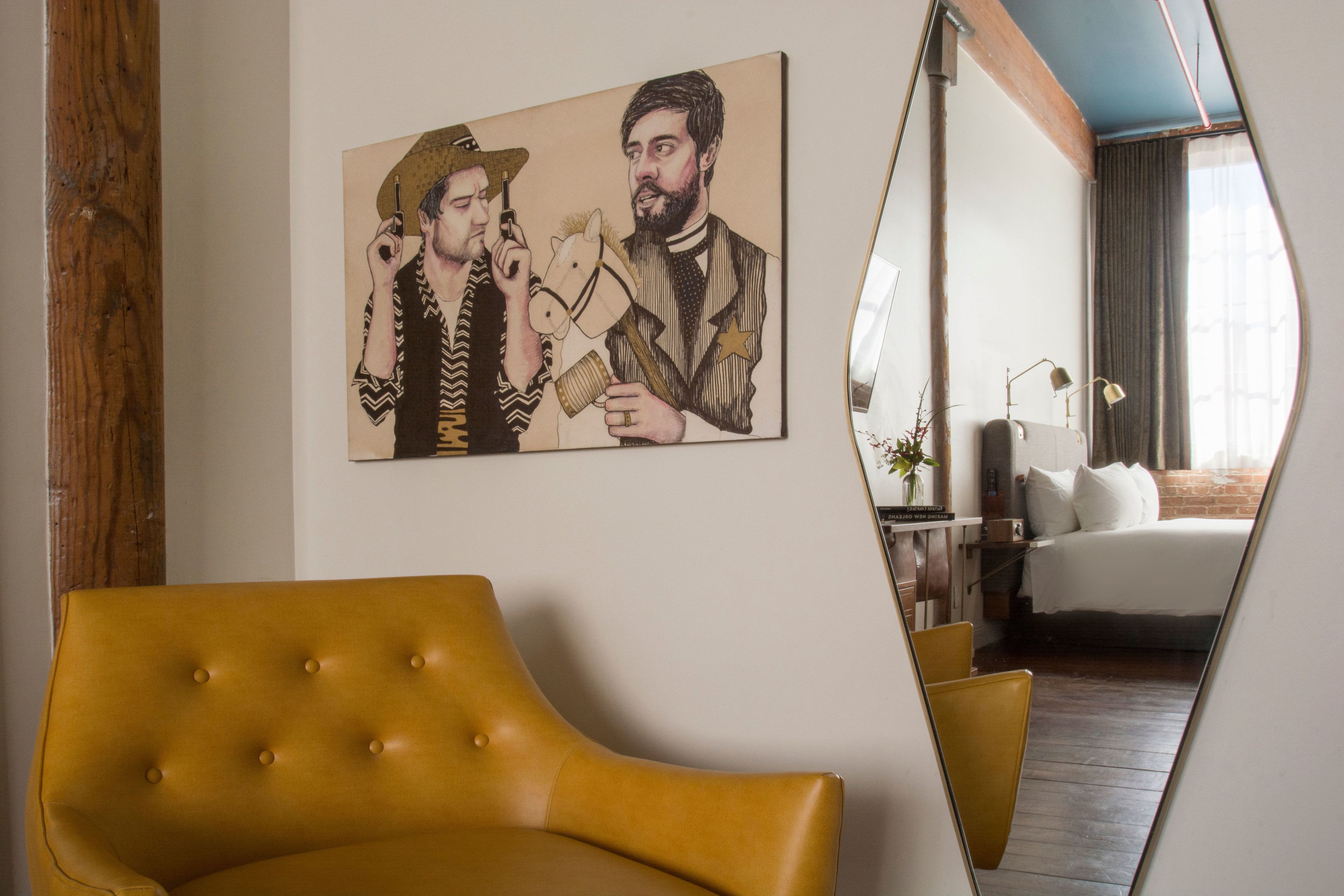Una habitación con un sillón amarillo, una cama con ropa de cama blanca, un cuadro en la pared y un espejo grande que refleja la habitación.
