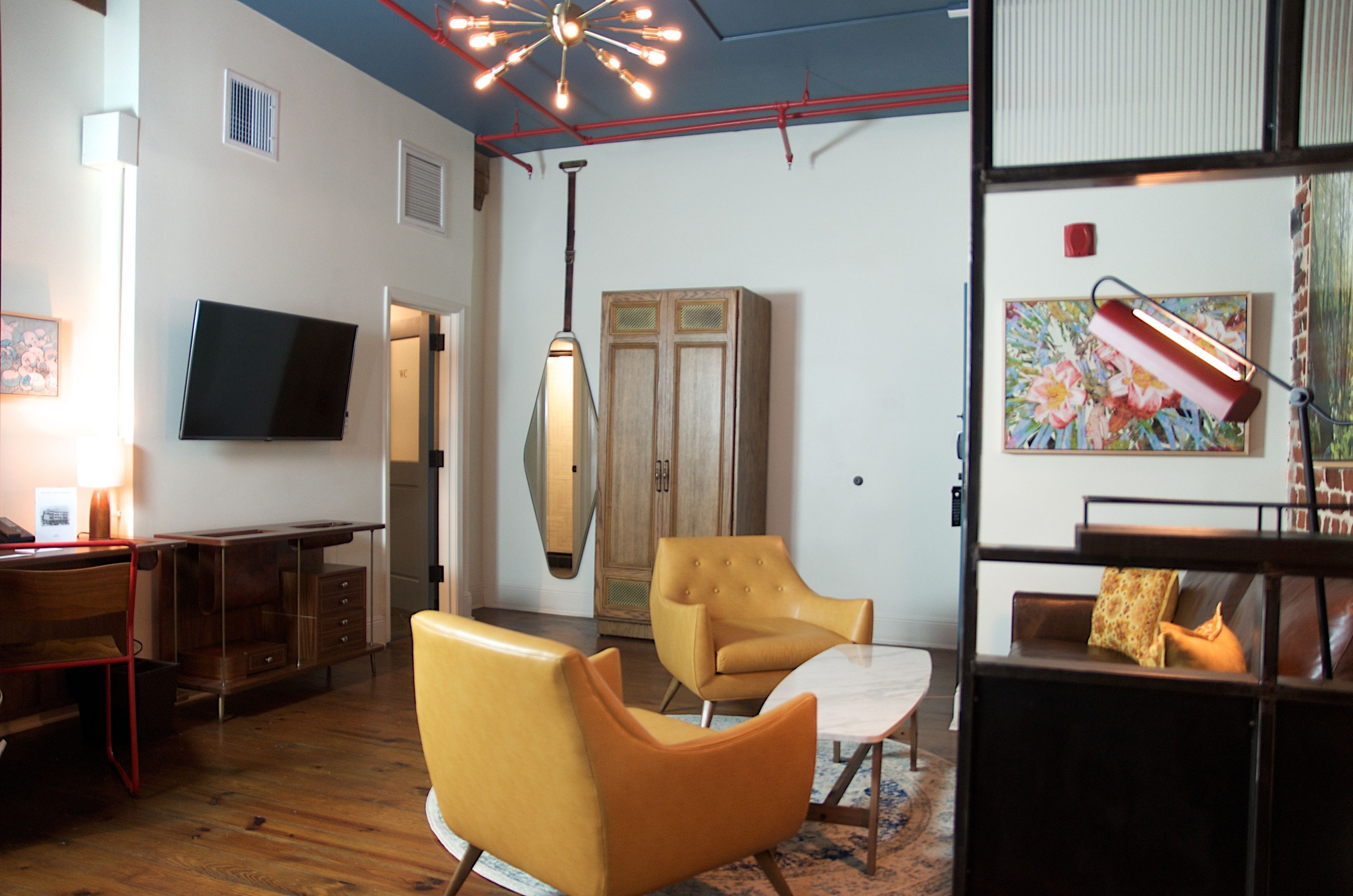 Een moderne woonkamer met een flatscreen televisie, een hanglamp, een houten kast en een bank.
